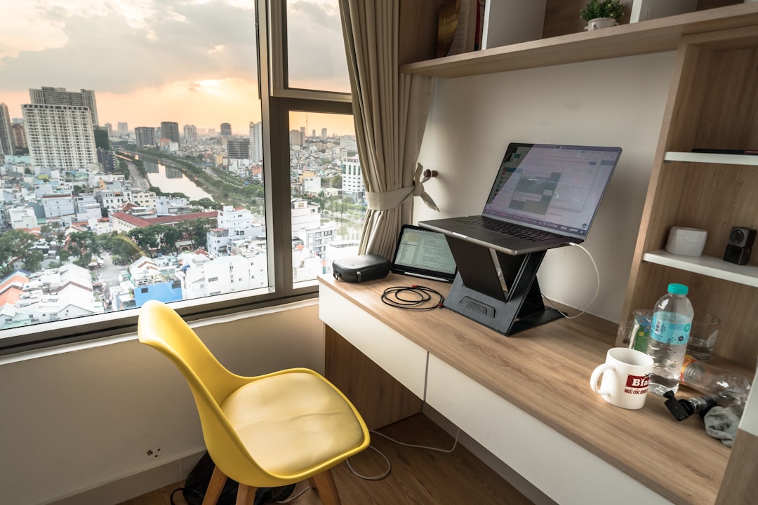 Desk with laptop and city view at sunset.