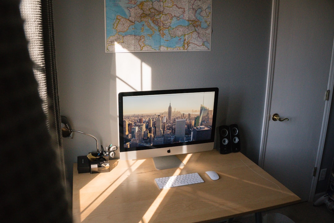 turned on silver iMac on beige wooden desk